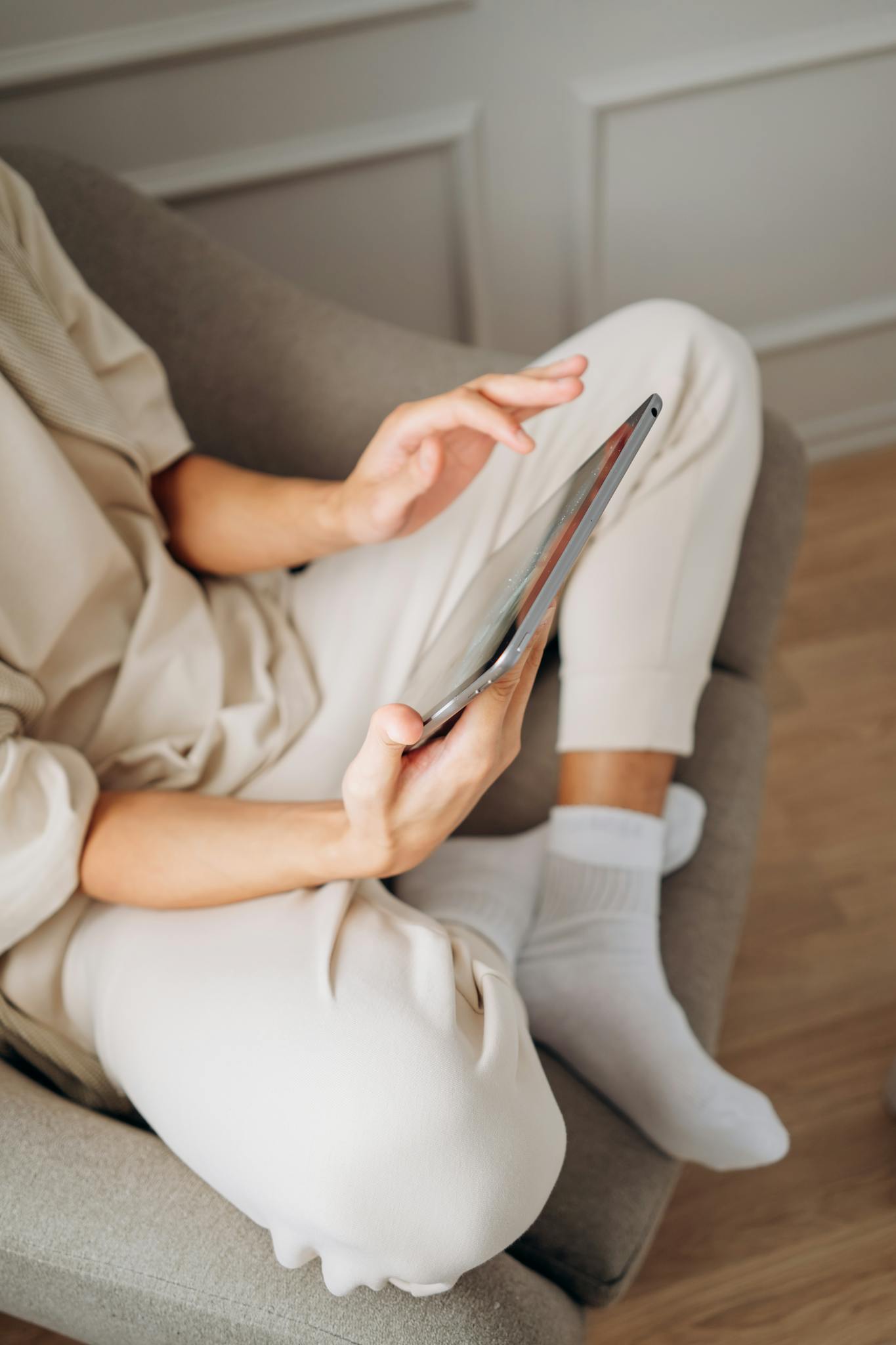 A person sits comfortably on a sofa using a tablet, depicting a relaxed lifestyle indoors.